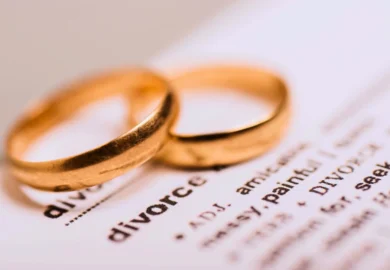 Two gold wedding rings resting on a page of text where the word "divorce" is prominently visible. Divorcing a spouse who hides assets