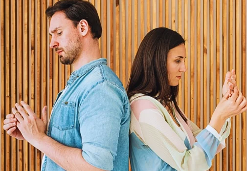 A man and a woman standing back-to-back against a wooden slat wall. Divorcing Later in Life
