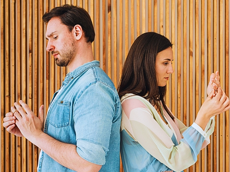 A man and a woman standing back-to-back against a wooden slat wall. Divorcing Later in Life