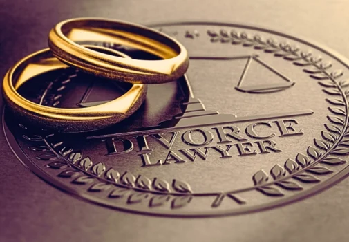Two gold wedding rings placed on a surface embossed with a seal that reads "DIVORCE LAWYER." Divided in Illinois Divorces