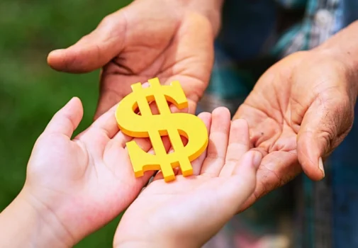 Adult hands placing yellow dollar sign in child's hands How Trusts, Inheritances, and Family Wealth Are Treated in Divorce.