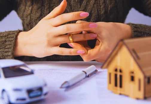 Woman removing wedding ring over divorce papers and models. Get Divorced Without Losing Everything