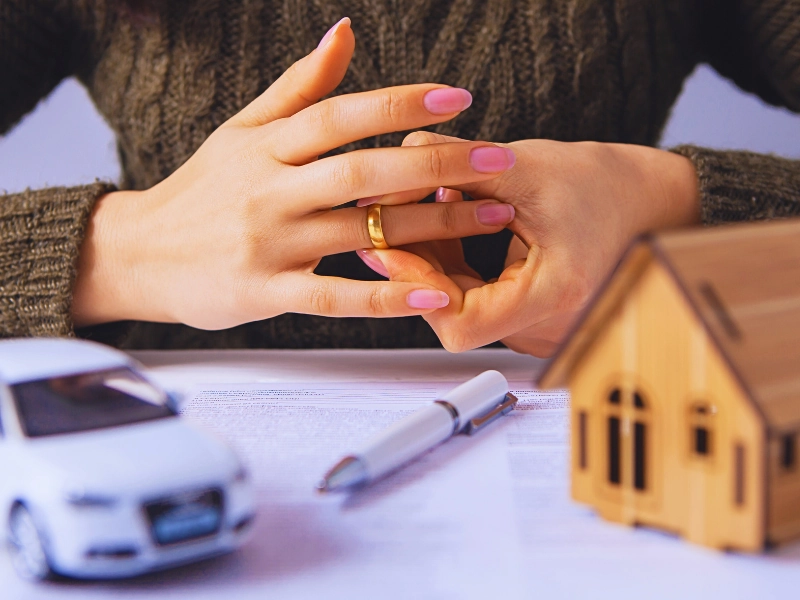 Woman removing wedding ring over divorce papers and models. Get Divorced Without Losing Everything