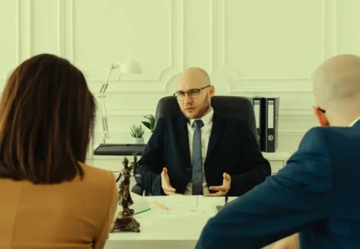A couple sits in front of a lawyer's desk; the couple is processing their divorce. Spouse Use Your Finances Against You