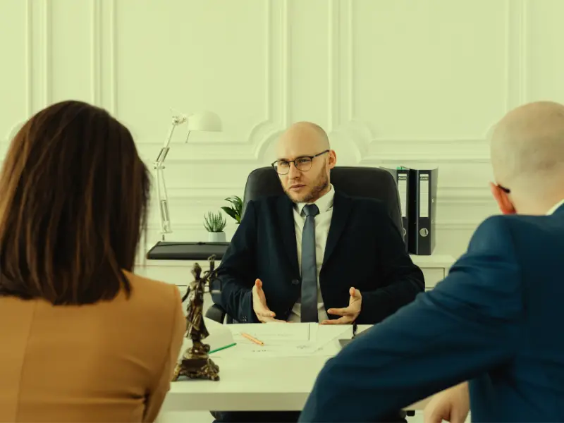 A couple sits in front of a lawyer's desk; the couple is processing their divorce. Spouse Use Your Finances Against You