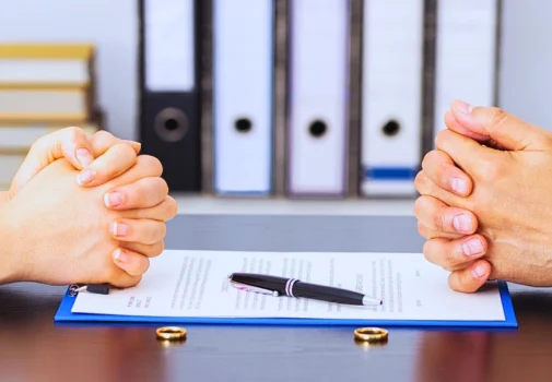Two people with clenched hands sit before divorce papers. divorce affects taxes