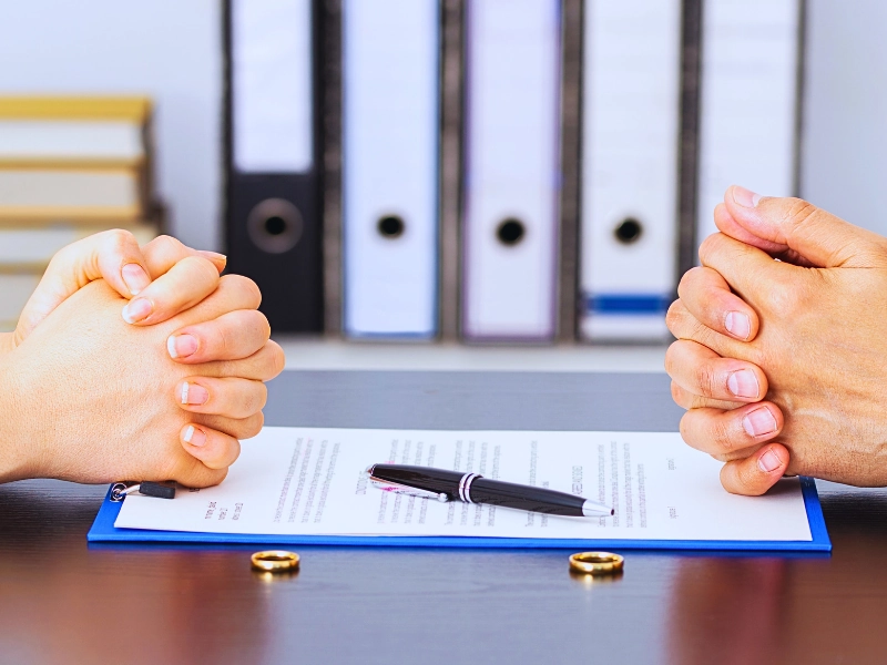 Two people with clenched hands sit before divorce papers. divorce affects taxes