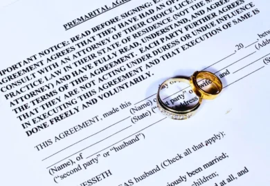 Two gold wedding rings placed on a premarital agreement. ask for a prenup