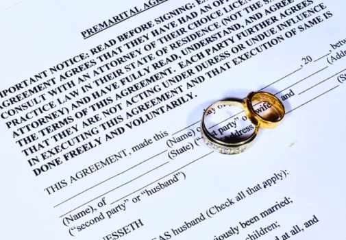 Two gold wedding rings placed on a premarital agreement. ask for a prenup