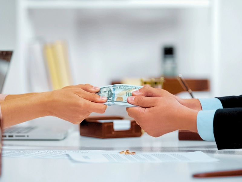 Two people handing over a stack of US dollar bills. protect your financial future
